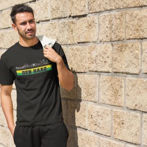 Man draagt een wit T-shirt met de skyline van Den Haag en de tekst “Den Haag” in groen-gele kleuren – ideaal voor trotse Hagenaren en supporters.