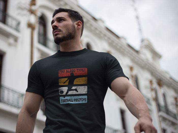 T-shirt met de tekst “My Blood Type? Football Positive” en een voetballer silhouet.