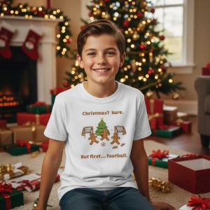 Wit kindermode T-shirt met grafische weergave van peperkoekmannetjes die voetballen bij een kerstboom.