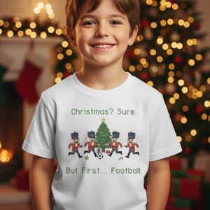 Wit kindermode T-shirt met grafische weergave van notenkrakersoldaten die voetballen bij een kerstboom.